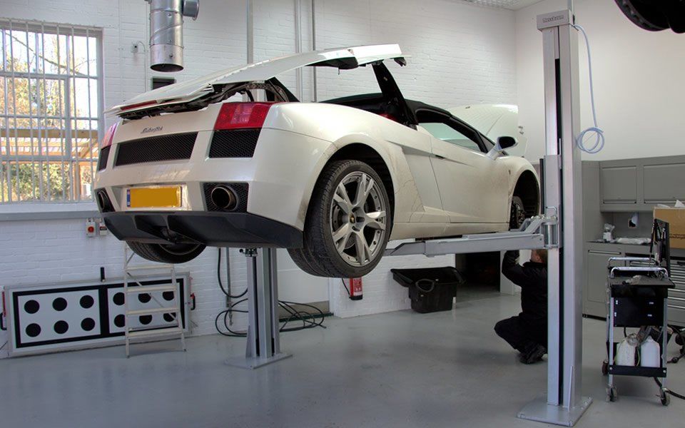 Vehicle lifted on fixed Nussbaum 2-post lift allowing mechanic to work safely with workshop tools close to hand